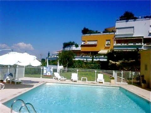 une piscine avec des chaises et un bâtiment dans l'établissement Parc de Diane ANTIBES RDJ, à Antibes