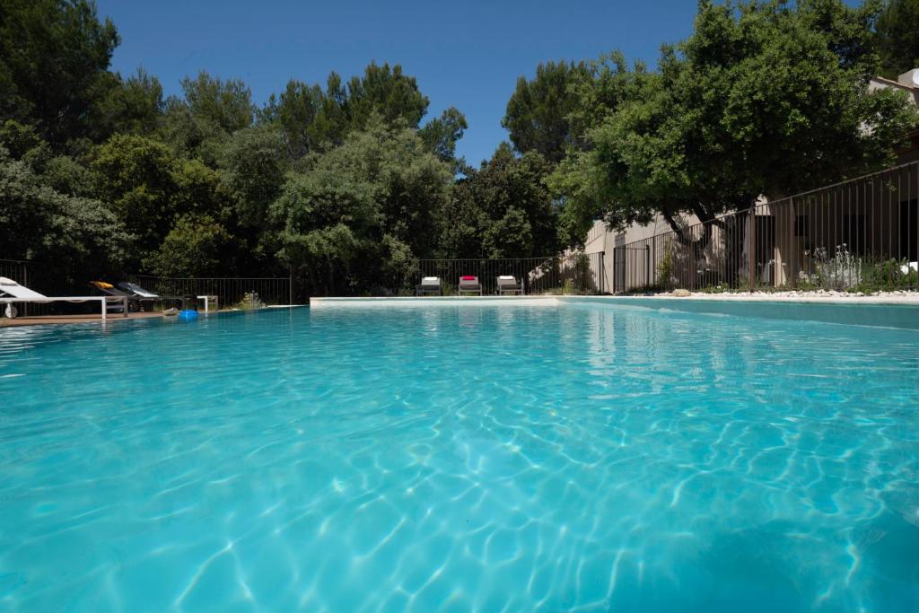 une grande piscine avec de l'eau bleue dans l'établissement La maison de Brigitte, à LʼIsle-sur-la-Sorgue
