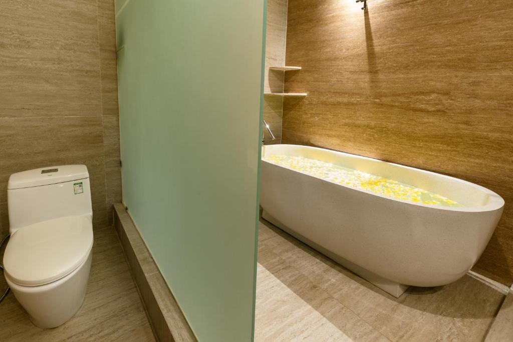 a bathroom with a white tub and a toilet at Bali Sunshine Nusa Dua in Nusa Dua