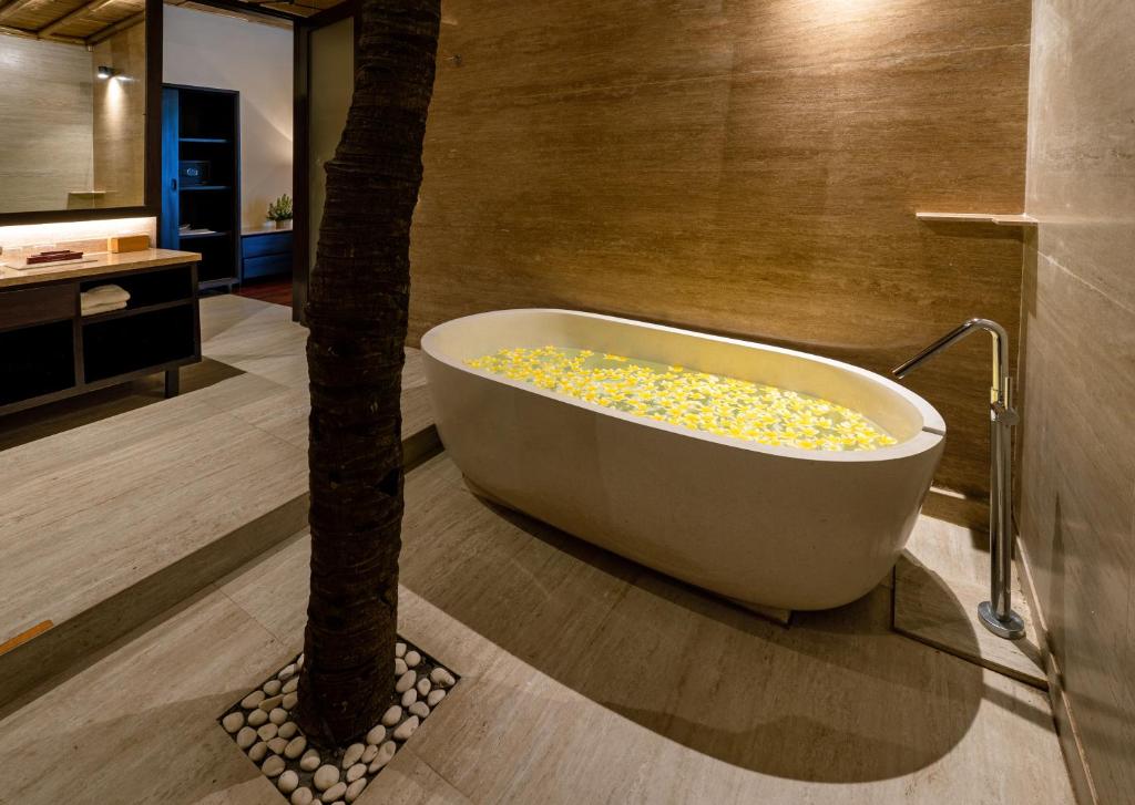 a bath tub sitting next to a palm tree in a bathroom at Bali Sunshine Nusa Dua in Nusa Dua