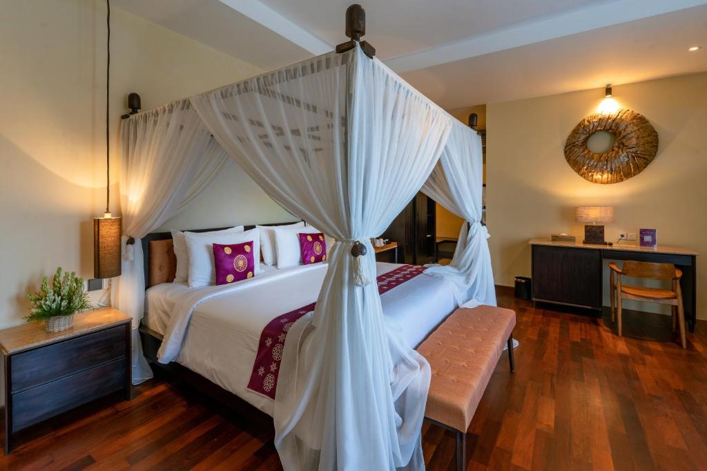 a bedroom with a large bed with a canopy at Bali Sunshine Nusa Dua in Nusa Dua