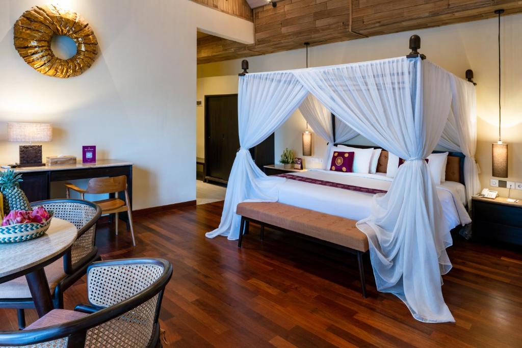 a bedroom with a canopy bed with a table and chairs at Bali Sunshine Nusa Dua in Nusa Dua