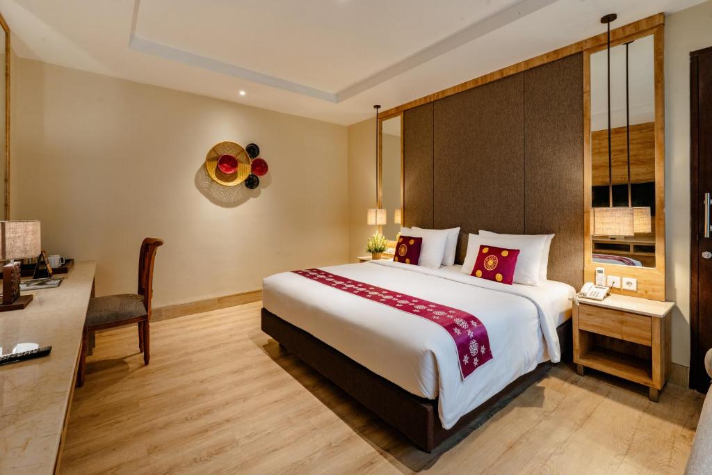 a hotel room with a large bed and a desk at Bali Sunshine Nusa Dua in Nusa Dua