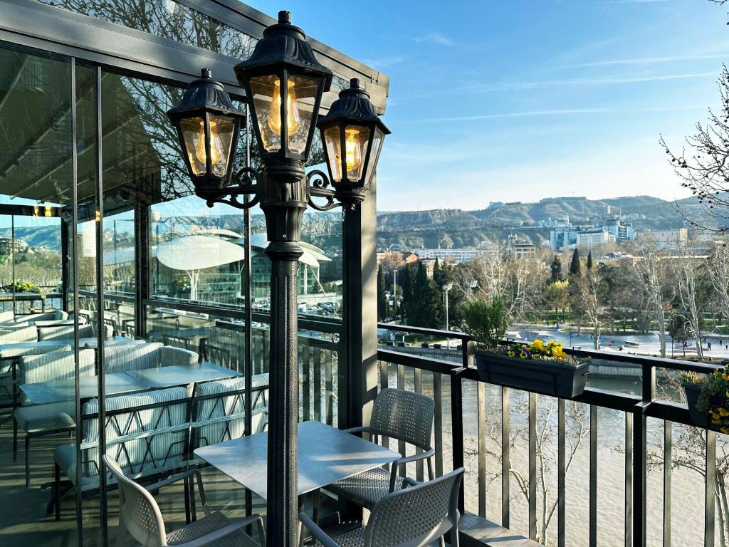 un restaurante con mesas y sillas en un balcón en River View Hotel Tbilisi, en Tiflis