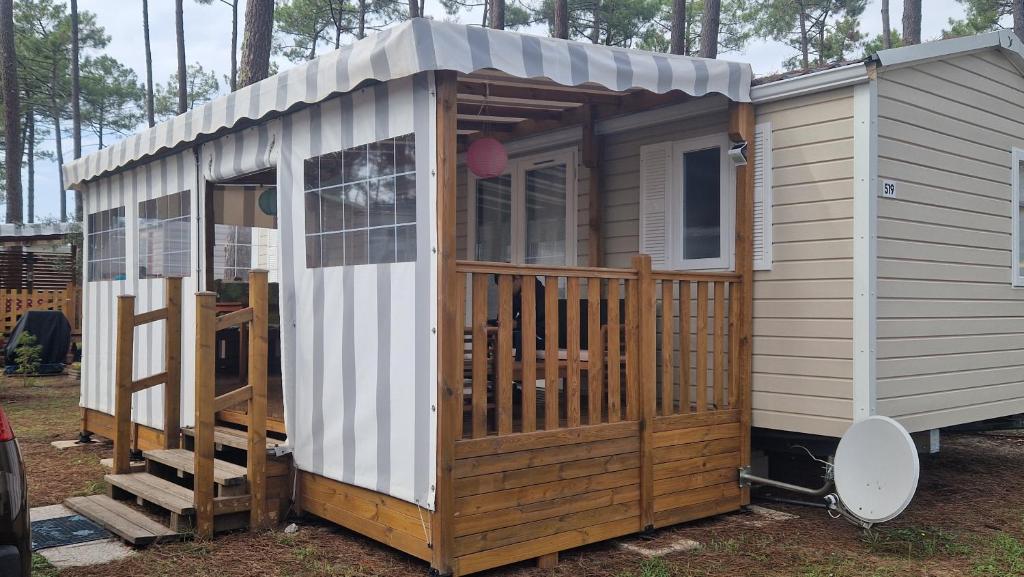 une petite maison avec un porche et une terrasse dans l'établissement Mobilhome les Dunes de Contis, à Saint-Julien-en-Born
