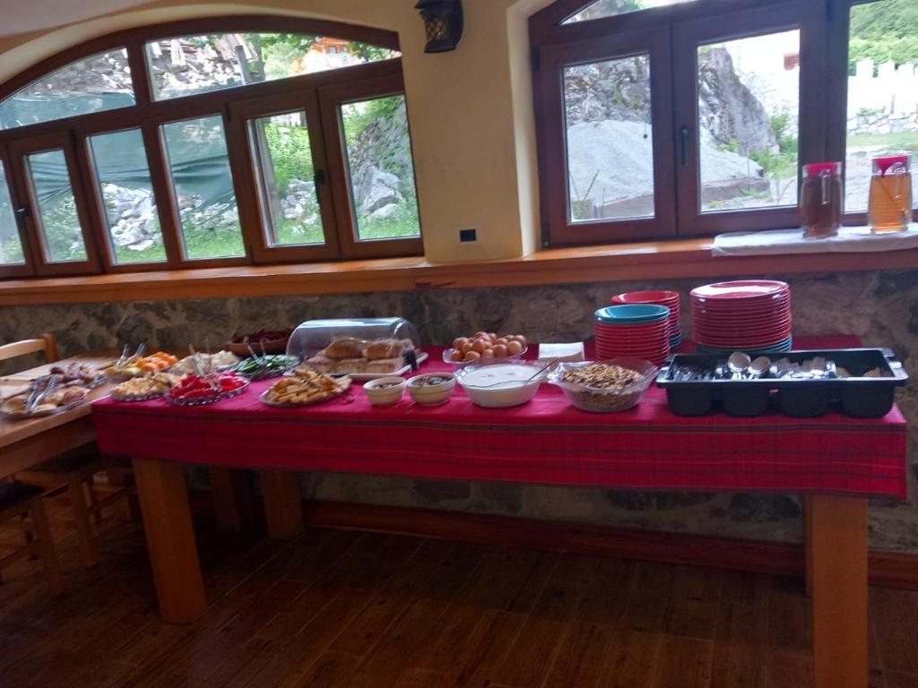 une table remplie de nourriture sur une table avec fenêtres dans l'établissement Hostel Quku i Valbones, à Valbonë