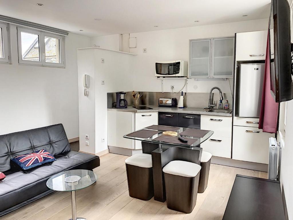 un salon avec un canapé et une cuisine dans l'établissement Appartement Central avec Terrasse Privative, Ascenseur, et Proche Plage - FR-1-361-353, à Granville