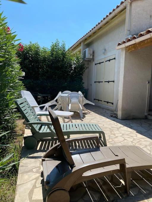 un ensemble de bancs en bois assis sur un patio dans l'établissement Jolie Villa 6 pers terrasse et Parking 400 m plage - V0736, à Vias