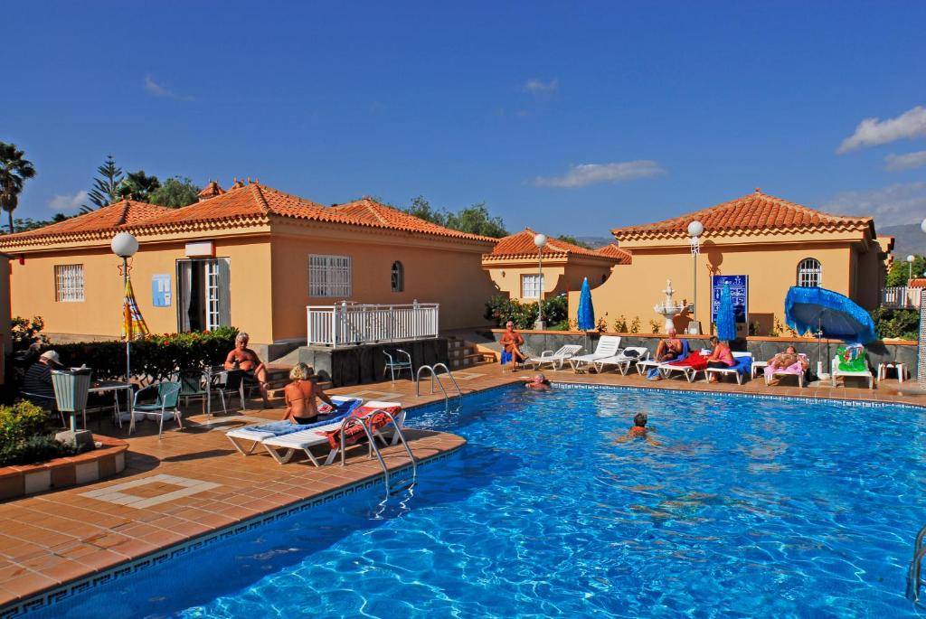 a swimming pool with people sitting in chairs in a house at Apartamentos Tara in Maspalomas