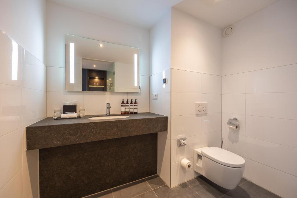a bathroom with a sink and a toilet and a mirror at Grand Hotel Amrâth Amsterdam in Amsterdam