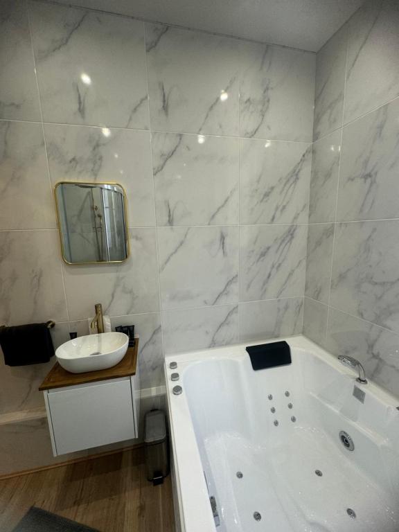 une salle de bain blanche avec une baignoire et un lavabo dans l'établissement L'Experience Appartement & SPA Privé CHAMBERY, à Chambéry