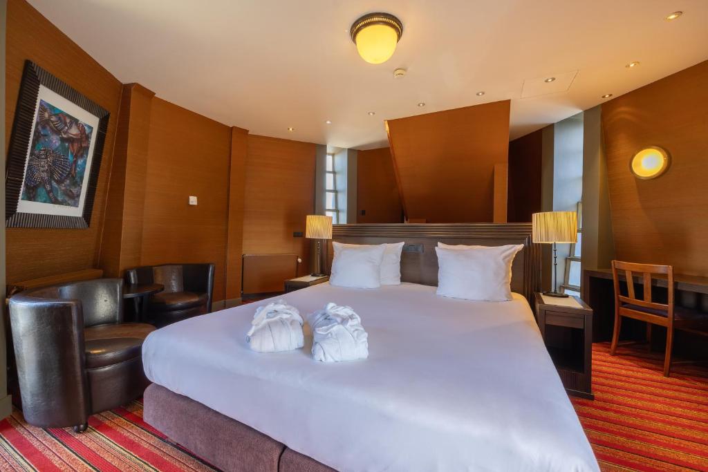a hotel room with a large white bed with two towels at Grand Hotel Amrâth Amsterdam in Amsterdam