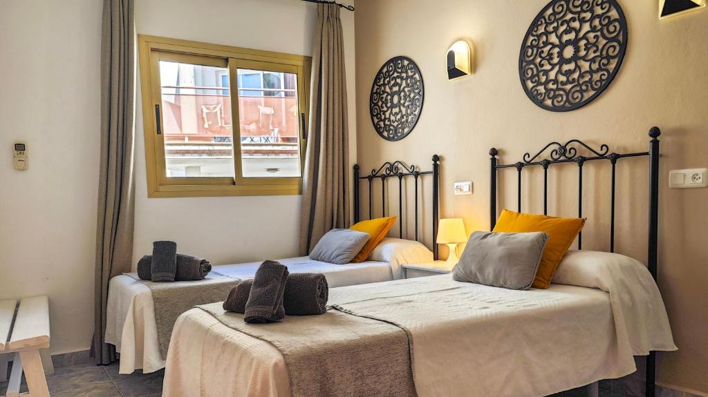 two beds in a room with a window at Hostal Dinamarca in San Antonio