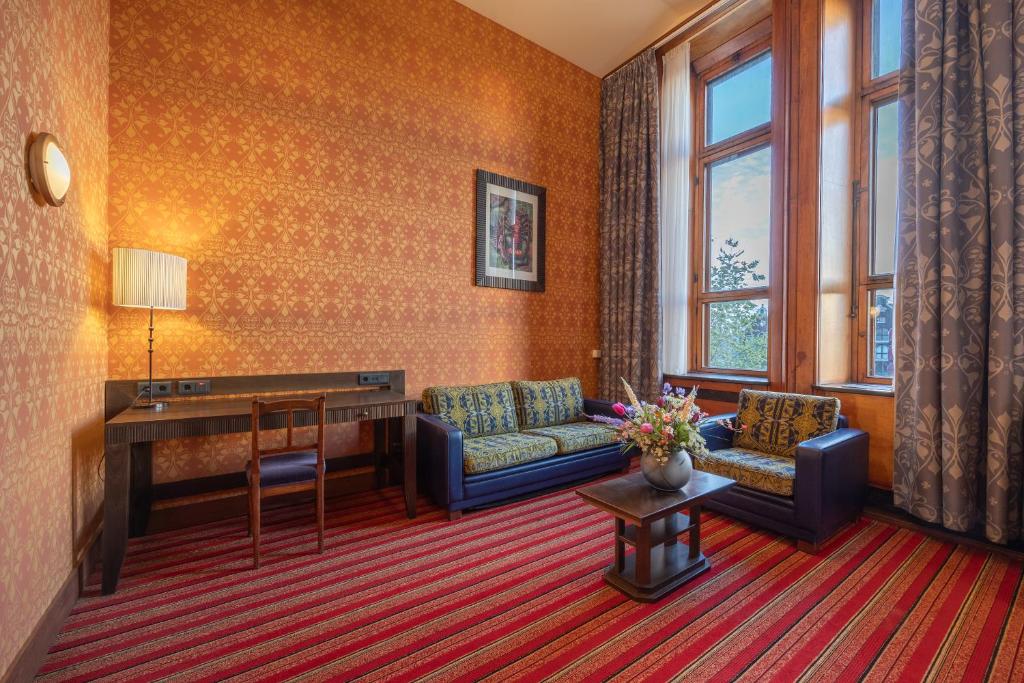 a living room with a couch and a desk at Grand Hotel Amrâth Amsterdam in Amsterdam