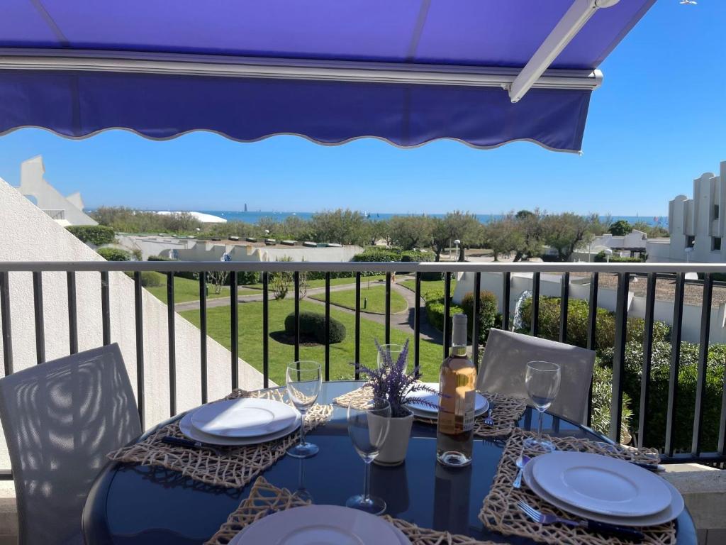 une table avec des assiettes et des verres sur un balcon dans l'établissement Apartment Le Parador-4 by Interhome, à La Grande Motte