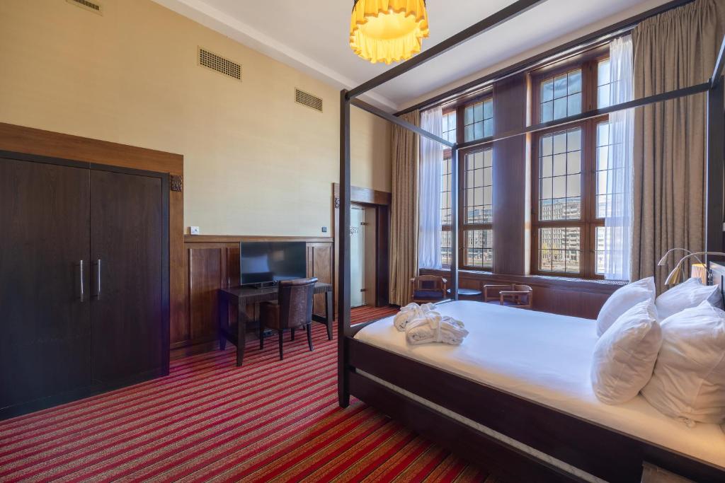a bedroom with a large bed with a large window at Grand Hotel Amrâth Amsterdam in Amsterdam