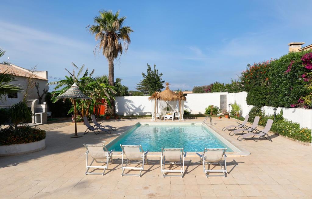 una piscina con sedie e una palma di Villa Alloro a Petrosino