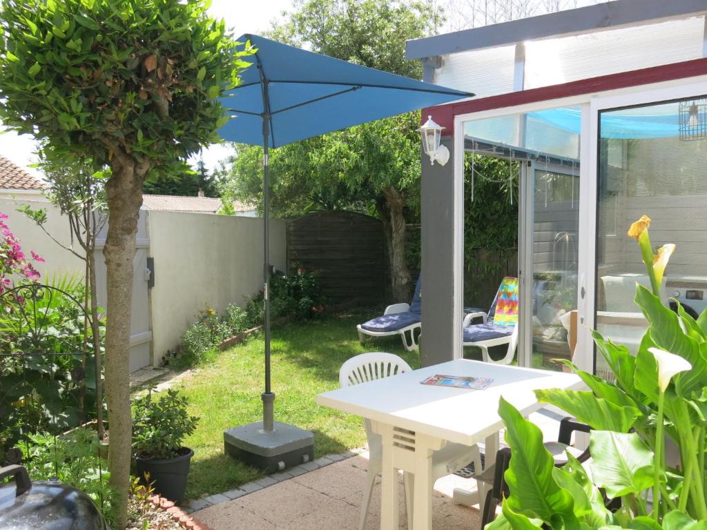 a patio with a table and a blue umbrella at Holiday Home Roses Tremières by Interhome in Talmont