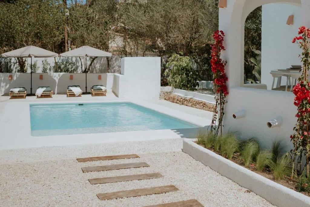 una piscina en un patio trasero con sillas y flores en Can Blau - Mediterranean Living, en Jávea