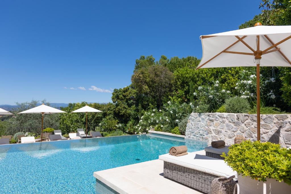 - une piscine avec des chaises et un parasol dans l'établissement La Réserve by Mougins Luxury Retreats, à Mougins