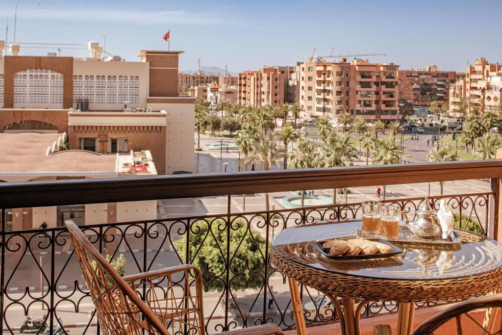 a table on a balcony with a view of a city at Red Hotel Marrakech in Marrakech