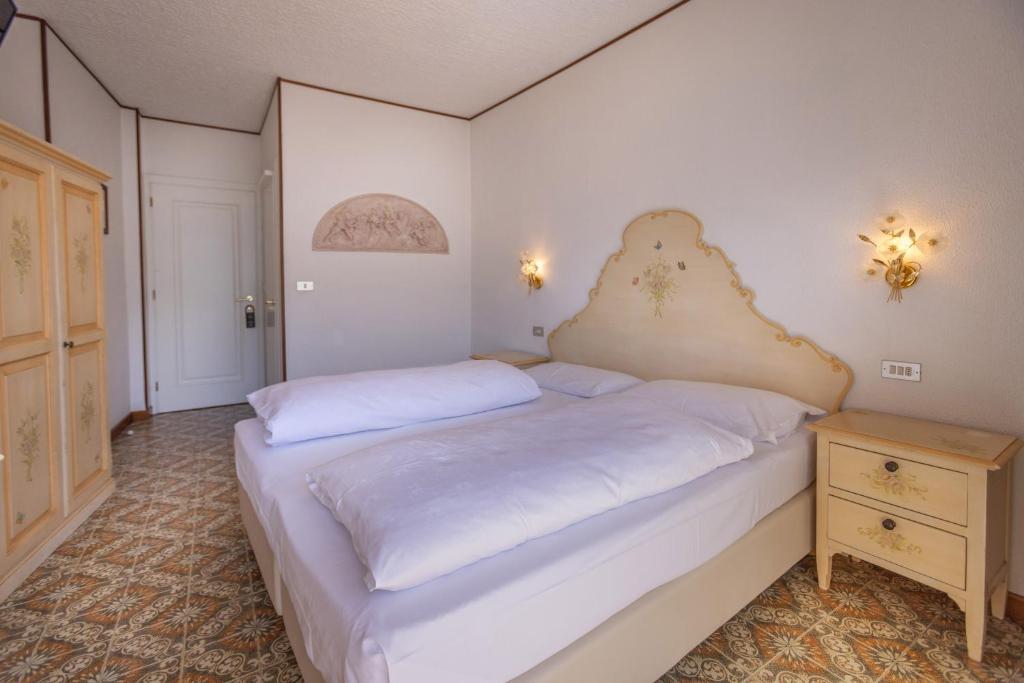a bedroom with a large white bed and a night stand at Hotel Villa Margherita in Limone sul Garda