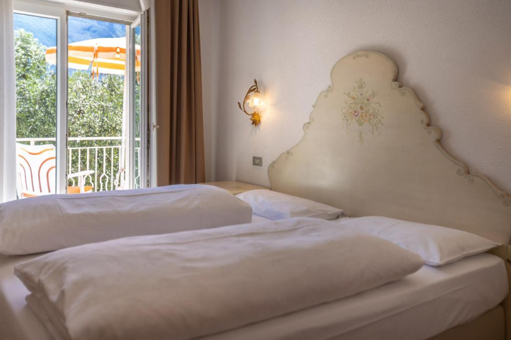 a hotel room with two beds and a balcony at Hotel Villa Margherita in Limone sul Garda