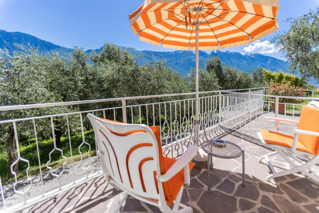 a patio with chairs and an umbrella on a balcony at Hotel Villa Margherita in Limone sul Garda
