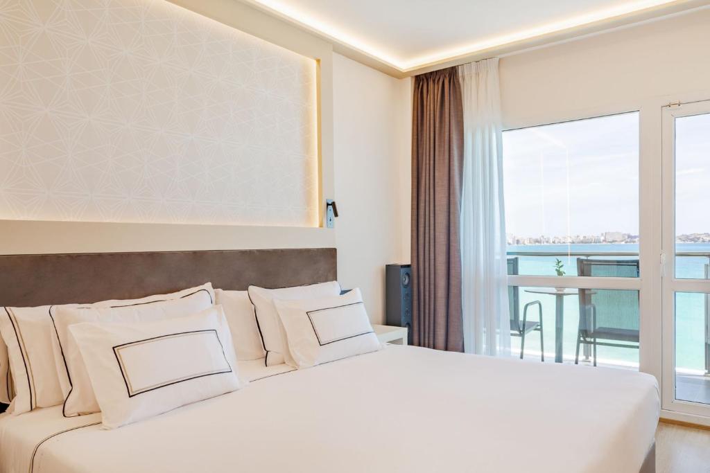 a bedroom with a large white bed with a large window at Melia Alicante in Alicante