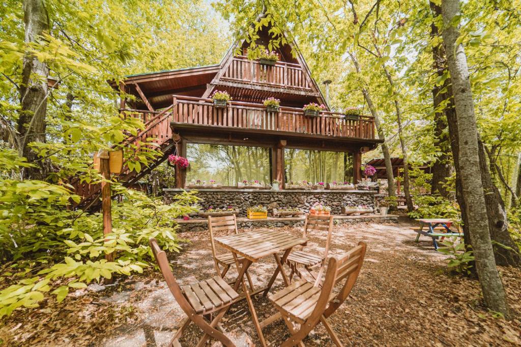 eine Holzhütte im Wald mit einem Tisch und Stühlen in der Unterkunft Matilde's Chalet Etna Nature House in Nicolosi