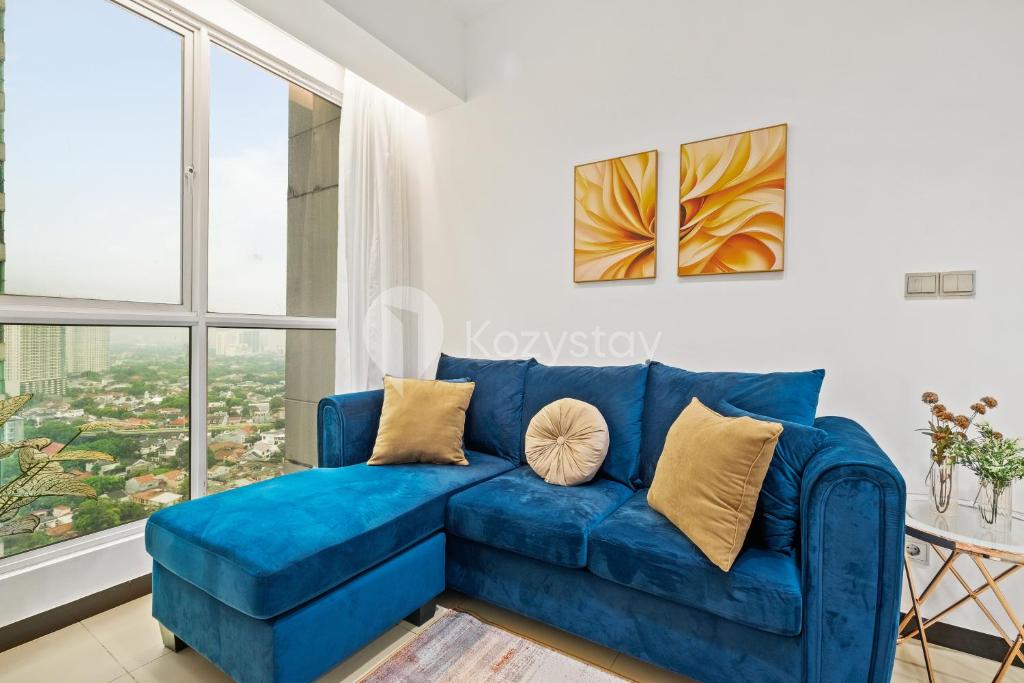 ein blaues Sofa im Wohnzimmer mit Fenster in der Unterkunft Vesta by Kozystay - Gandaria in Jakarta