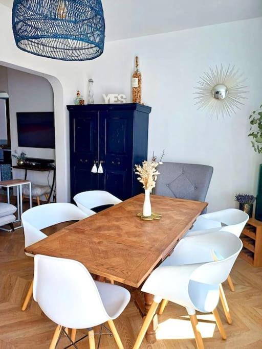 une salle à manger avec une table en bois et des chaises blanches dans l'établissement Charmant 3pièces près de Cannes, au Cannet