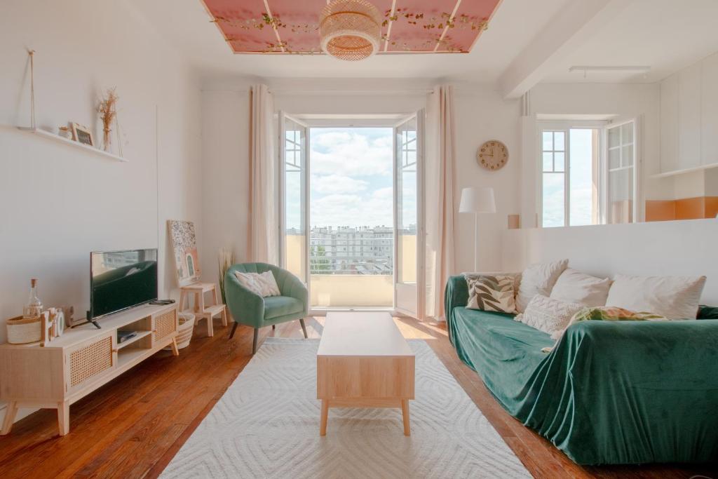- un salon avec un canapé vert et une télévision dans l'établissement Appartement Spacieux - Vue Pyrénées - Hypercentre, à Tarbes
