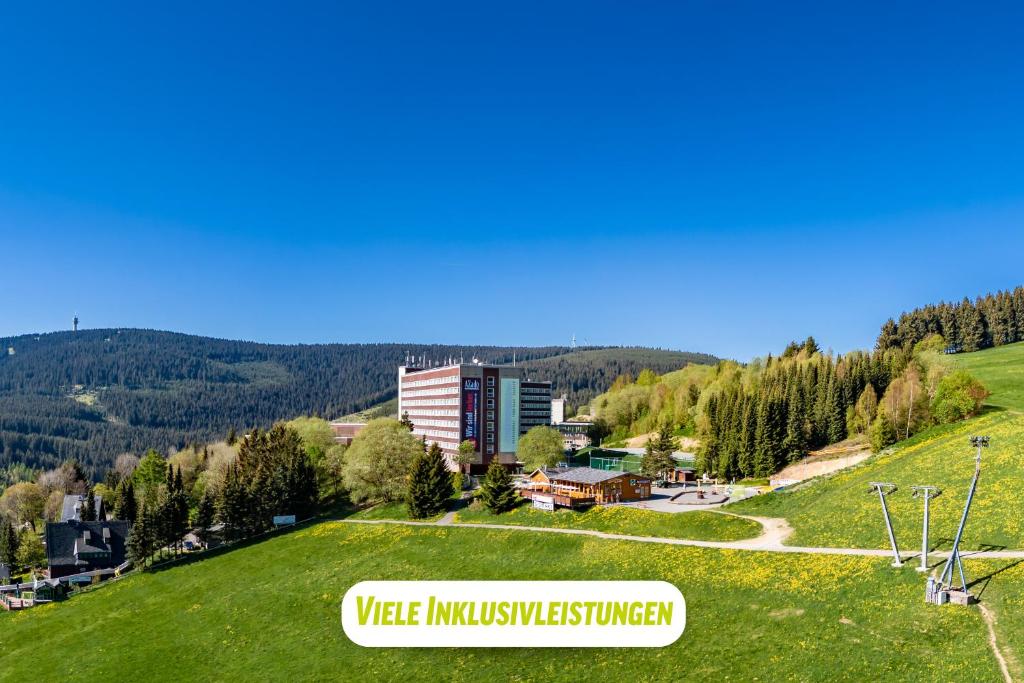 un edificio en una colina con un campo verde en AHORN Hotel Am Fichtelberg, en Kurort Oberwiesenthal