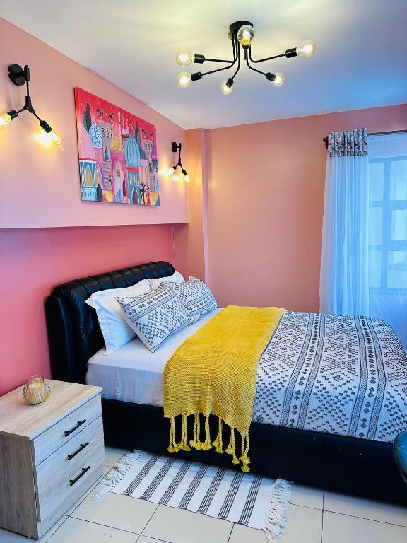 a bedroom with a bed and a pink wall at Cozy Home Near Wilson Airport & Giraffe Center in Nairobi