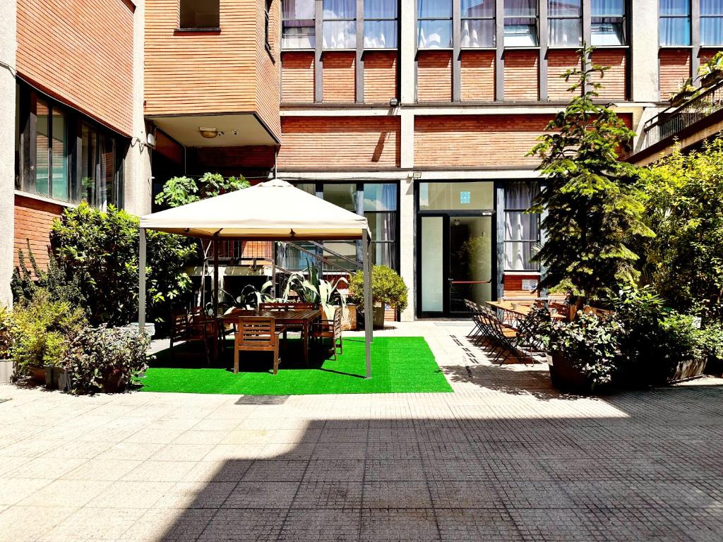 un patio con mesa y sombrilla frente a un edificio en Mio Hostel en Milán