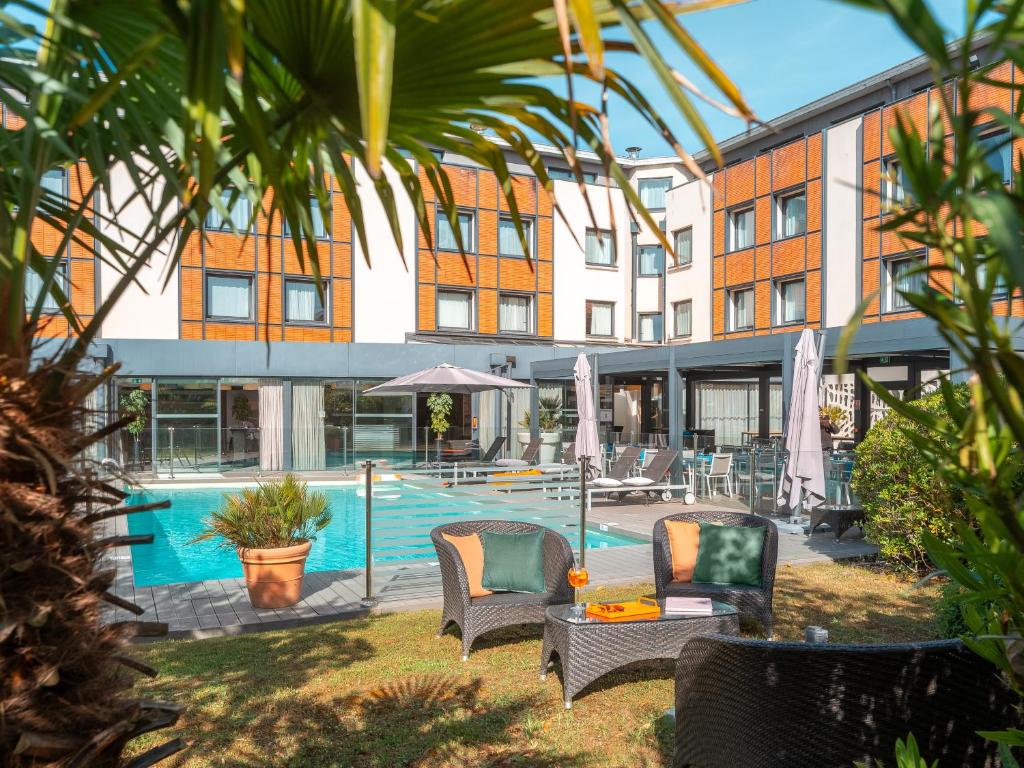 un hotel con piscina y sillas y un edificio en Holiday Inn Toulouse Airport, an IHG Hotel en Blagnac