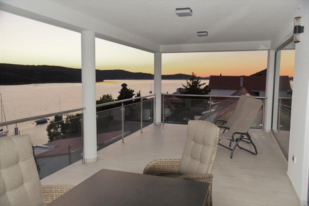 een balkon met een tafel en stoelen en uitzicht op het water bij Villa Pina Tisno in Tisno