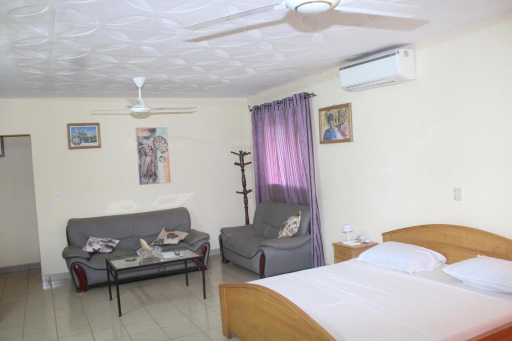 - une chambre avec un lit, un canapé et une chaise dans l'établissement Residence Diane, à Ouagadougou