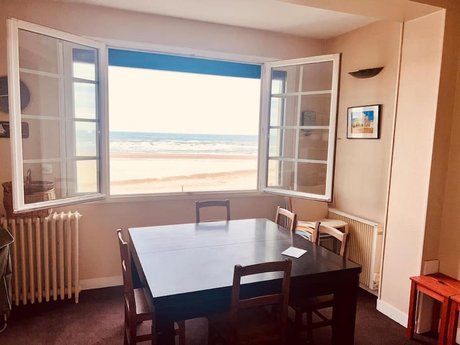une salle à manger avec une table et une vue sur la plage dans l'établissement Appartement Vue Mer, à Trouville-sur-Mer