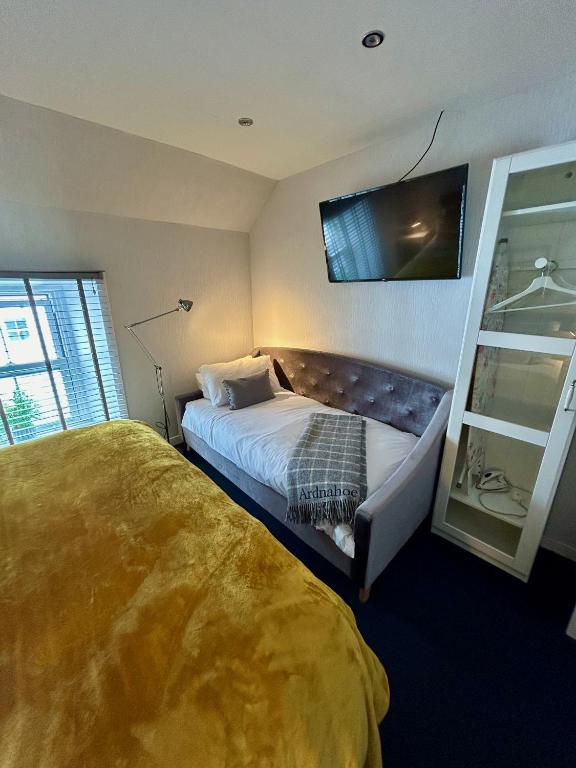 a bedroom with two beds and a tv on the wall at Lochindaal Hotel in Port Charlotte