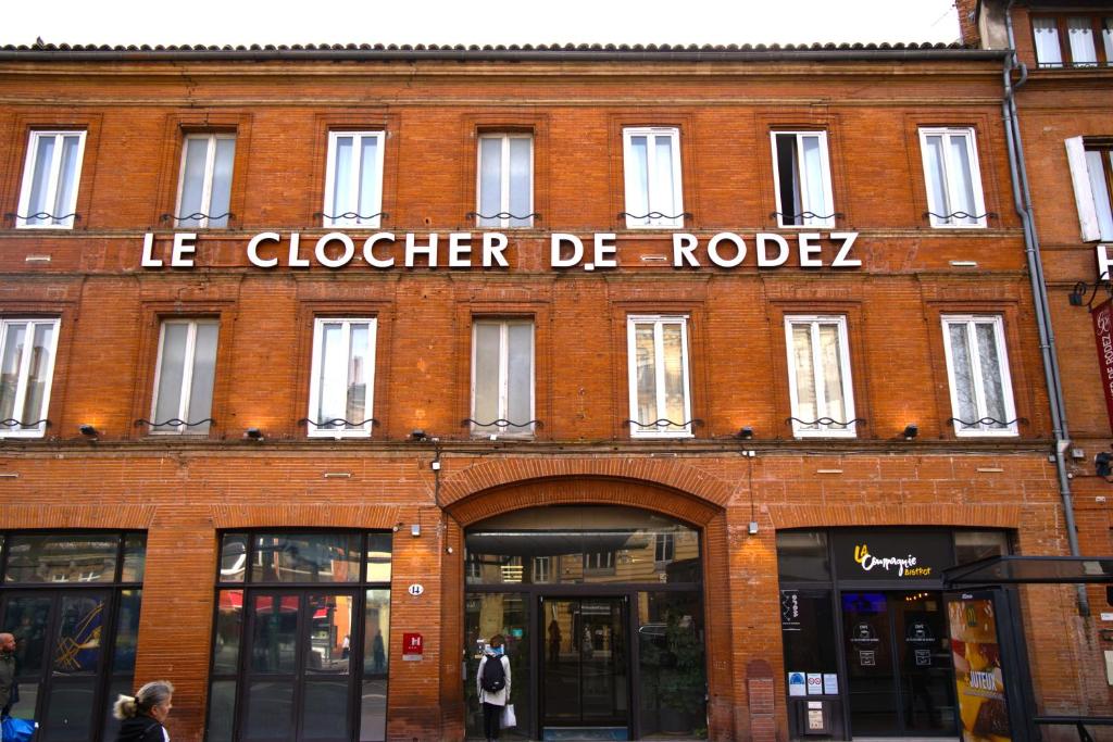 un bâtiment en brique rouge avec un panneau. dans l'établissement Le Clocher de Rodez Centre Gare, à Toulouse