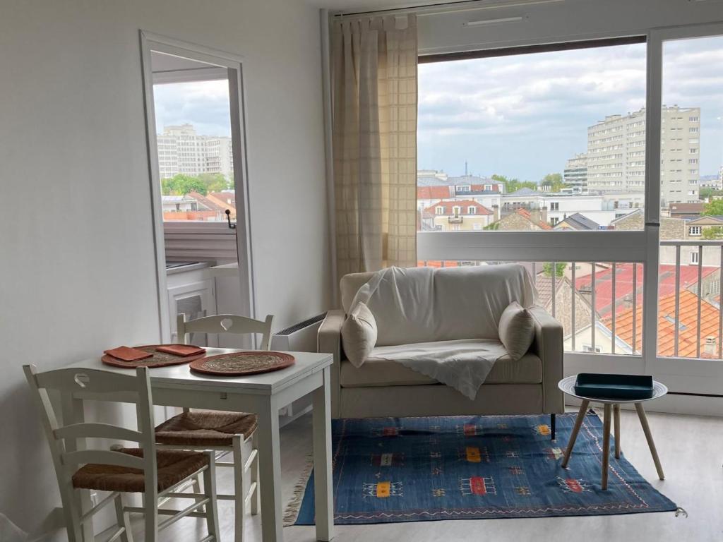 - un salon avec une chaise, une table et une fenêtre dans l'établissement Studio Spacieux vue sur Paris et Tour Eiffel Proche Paris, à Fontenay-aux-Roses
