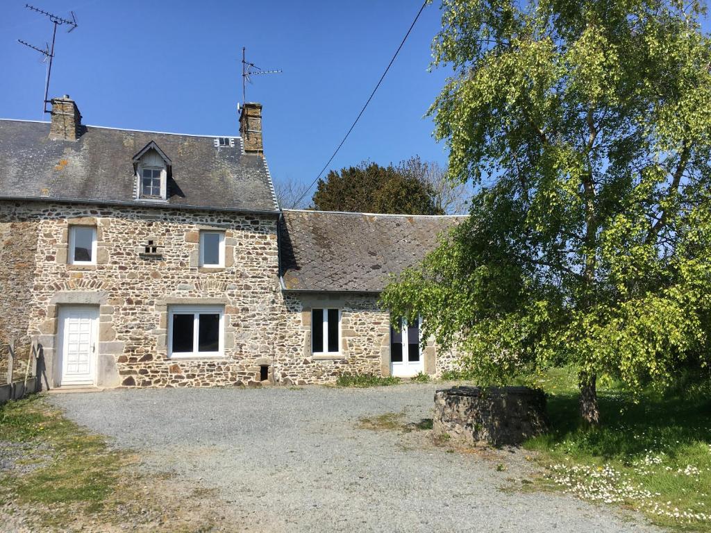 une vieille maison en pierre avec un arbre en face de celle-ci dans l'établissement Charmante maison normande à Brainville à 10mn de la mer, à Brainville