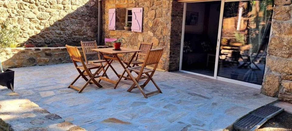 eine Terrasse mit einem Tisch und Stühlen an einer Steinmauer in der Unterkunft Gite avec piscine et terrain in Valgorge