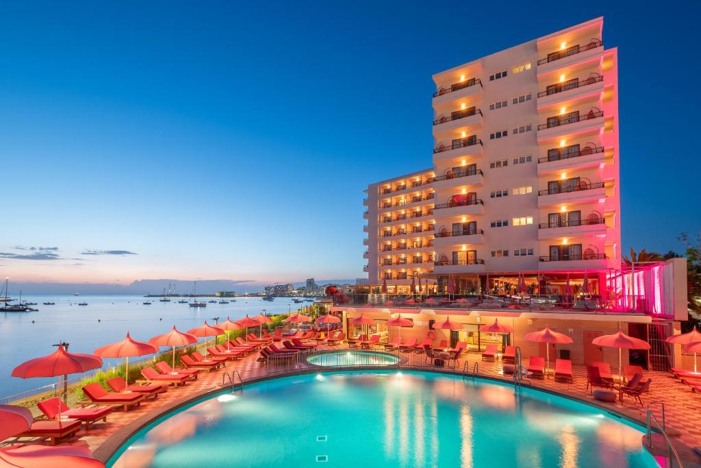 um hotel com uma piscina com cadeiras e guarda-sóis em NYX Hotel Ibiza by Leonardo Hotels-Adults Only em Baía de San Antonio