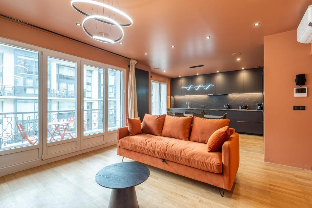 - un canapé orange dans une chambre avec fenêtres dans l'établissement L'OASIS T3 Centre ville, à Annecy