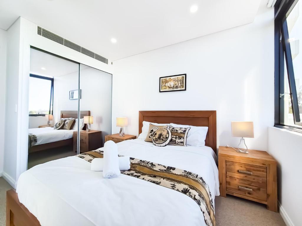 悉尼Relaxing 1BR w Pools & SPA, Gym in Olympic Park的有两张床和一面镜子的卧室