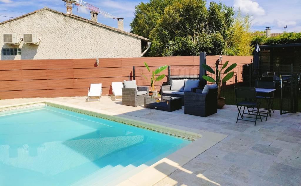 a swimming pool with chairs and a table next to a fence at Appart 1 ch rénové avec piscine in Morières-lès-Avignon