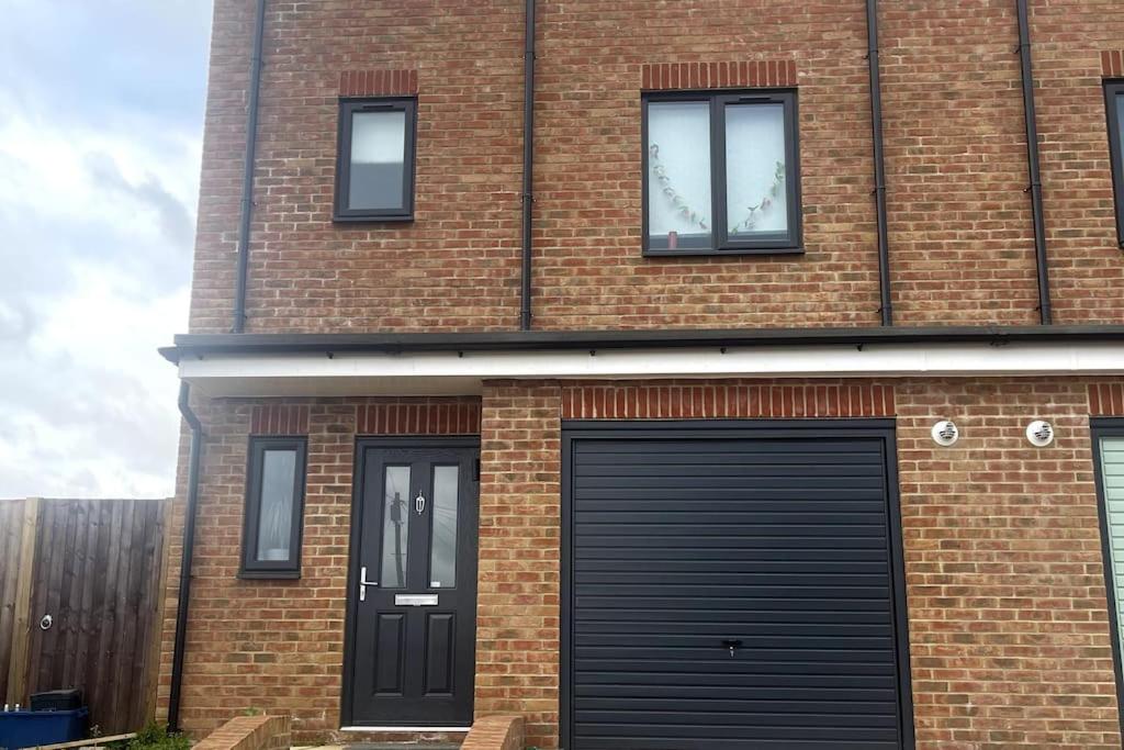 Un edificio de ladrillo con dos puertas de garaje negras. en Ile, en Aldershot